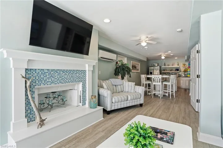 Living area with ceiling fan, a fireplace, light wood finished floors, and recessed lighting