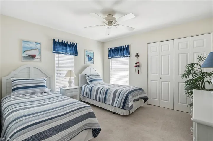 Bedroom with light colored carpet, a ceiling fan, and a closet