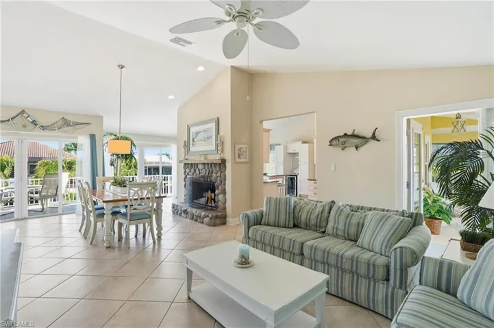 Living area featuring lofted ceiling, light tile patterned floors, a ceiling fan, a fireplace, and beverage cooler