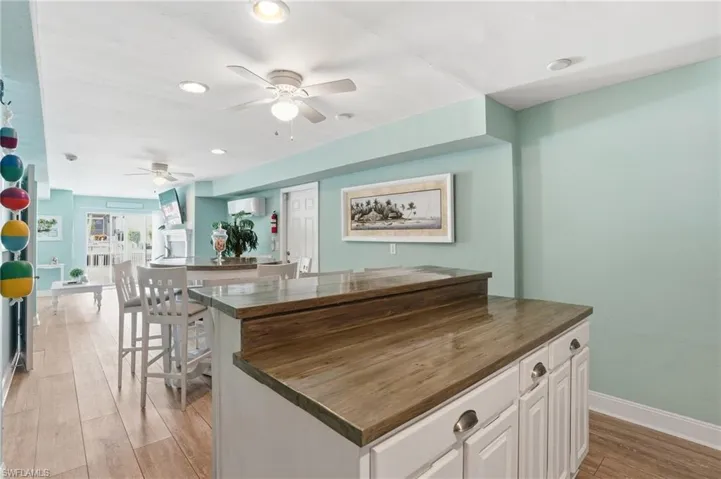 Kitchen featuring white cabinets, light wood-style floors, ceiling fan, wooden counters, and recessed lighting