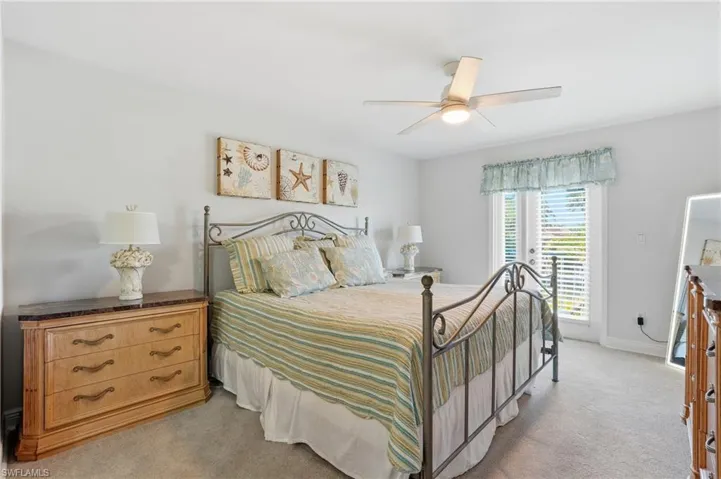 Bedroom featuring light carpet, a ceiling fan, and access to exterior