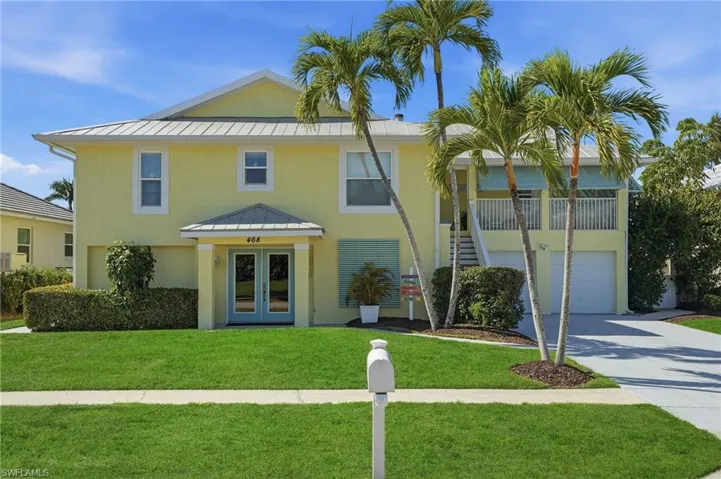 View of front facade with metal roof, french doors, a front lawn, concrete driveway, and stucco siding
