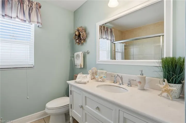 Bathroom with vanity, a tile shower, and light tile patterned flooring