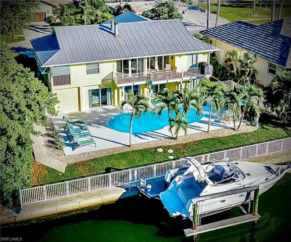 Back of house featuring a balcony, a patio area, an outdoor pool, stucco siding, and a metal roof