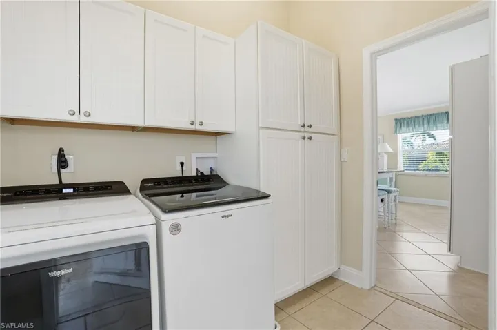 Laundry area with cabinet space, light tile patterned flooring, and washing machine and clothes dryer