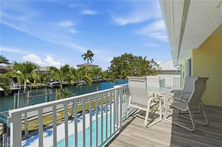 Balcony featuring view of pool, a water view, and outdoor dining area