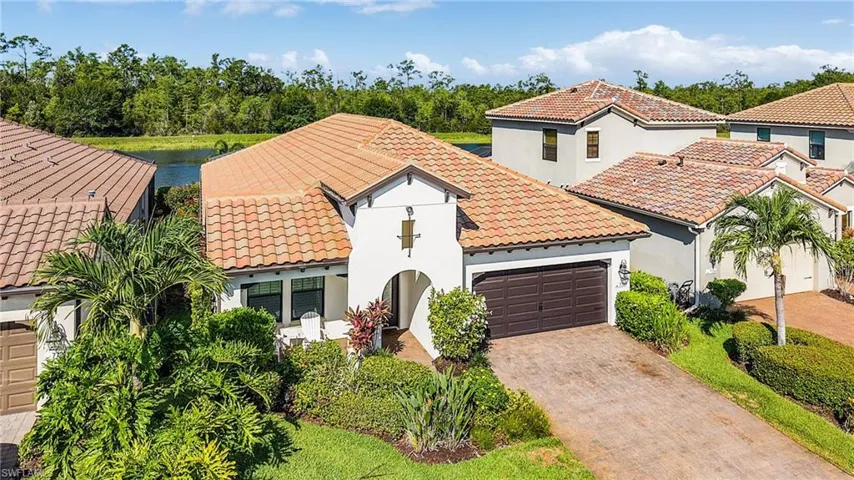 Mediterranean / spanish home with a tile roof, a garage, stucco siding, and driveway