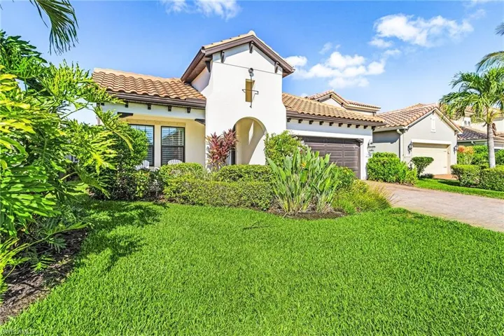 Mediterranean / spanish house with an attached garage, a tile roof, a front yard, and stucco siding