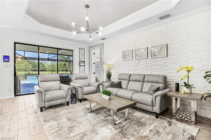 Living room with a tray ceiling, crown molding, and a chandelier