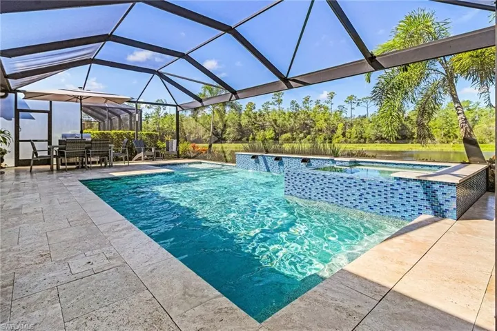 Outdoor pool featuring an in-ground hot tub, a patio, glass enclosure, and outdoor dining area