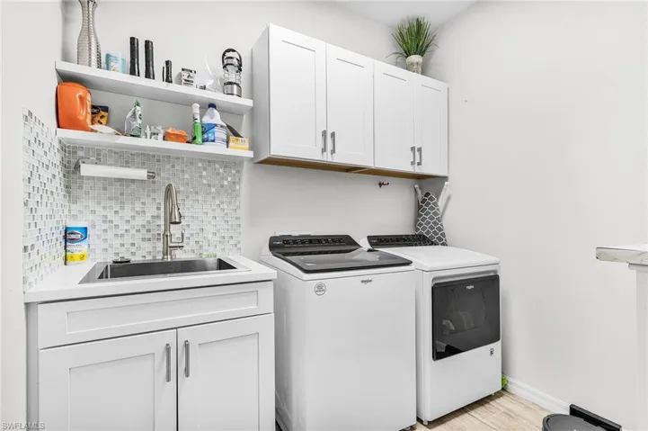 Washroom with separate washer and dryer, cabinet space, and light wood finished floors