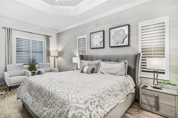 Bedroom featuring wood finished floors, crown molding, and a raised ceiling