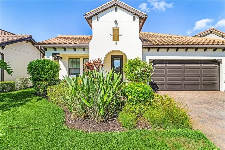 Mediterranean / spanish-style house featuring a tile roof, a garage, driveway, a front yard, and stucco siding