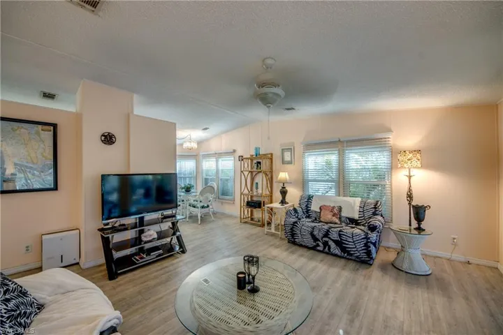 Living room with wood-type flooring, lofted ceiling, and a healthy amount of sunlight