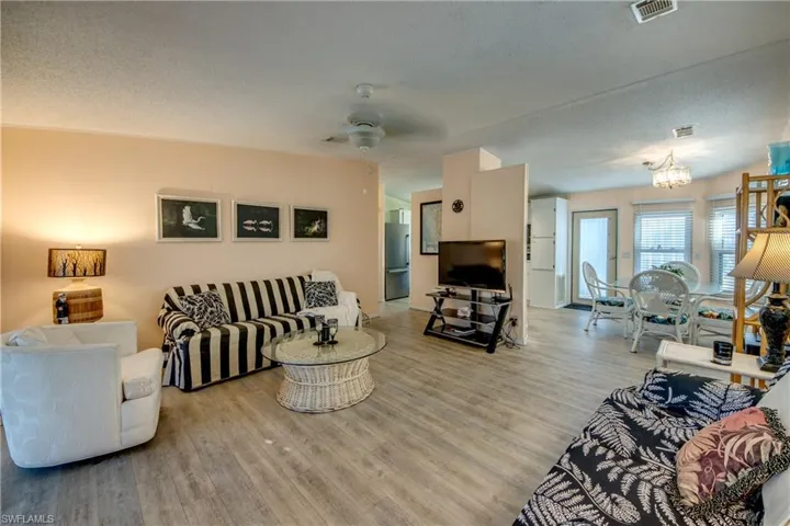 Living room featuring a textured ceiling, light hardwood / wood-style flooring, and ceiling fan with notable chandelier