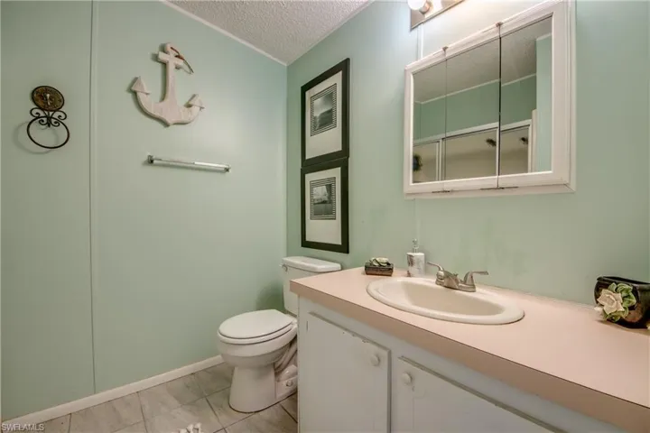 Bathroom featuring tile patterned flooring, vanity, toilet, and a textured ceiling