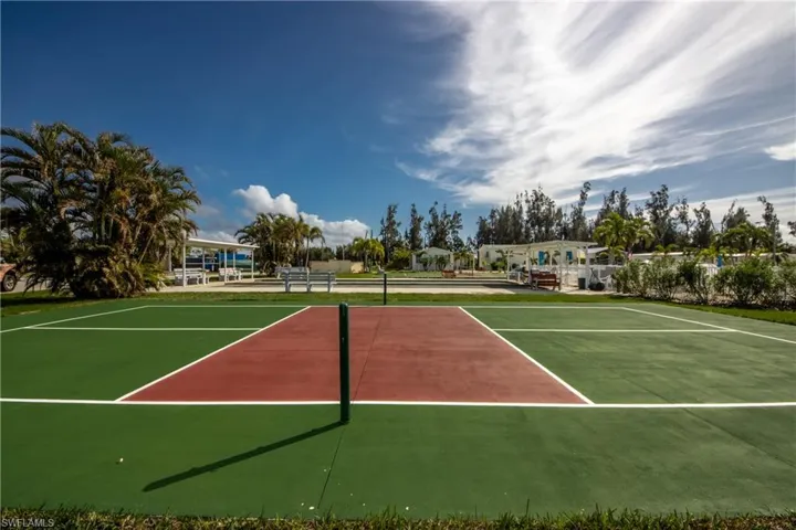 View of tennis court featuring basketball hoop