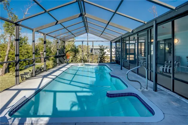 View of pool featuring glass enclosure and a patio