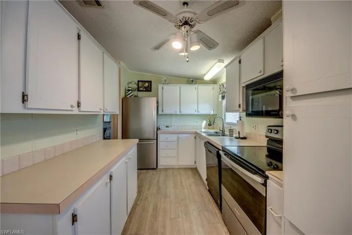Kitchen featuring black appliances, white cabinetry, and light hardwood / wood-style flooring