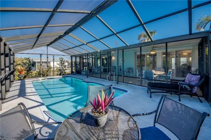 View of swimming pool featuring outdoor lounge area, a patio, glass enclosure, and ceiling fan