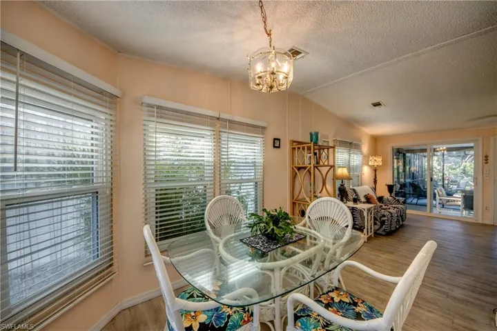 Dining area featuring a textured ceiling, hardwood / wood-style flooring, vaulted ceiling, and a notable chandelier