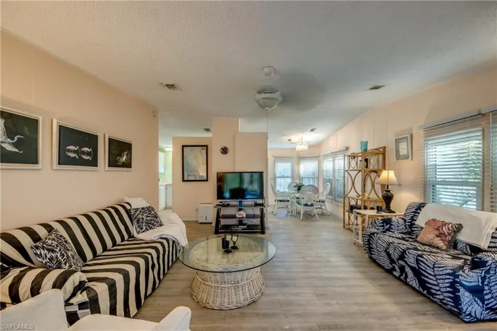 Living room with a textured ceiling, light hardwood / wood-style flooring, ceiling fan, and lofted ceiling