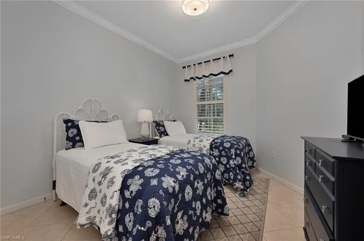 Bedroom with crown molding and light tile patterned floors