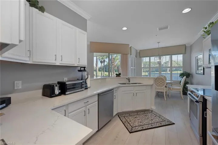 Kitchen featuring crown molding, white cabinetry, appliances with stainless steel finishes, a peninsula, and light wood-type flooring