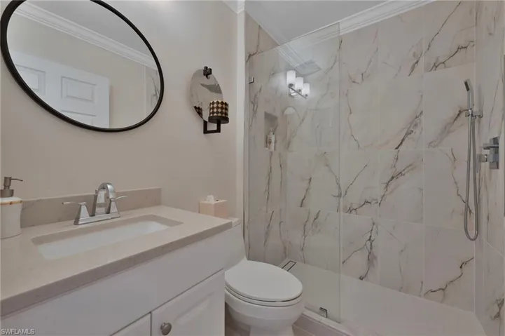 Full bathroom featuring ornamental molding, vanity, and a marble finish shower