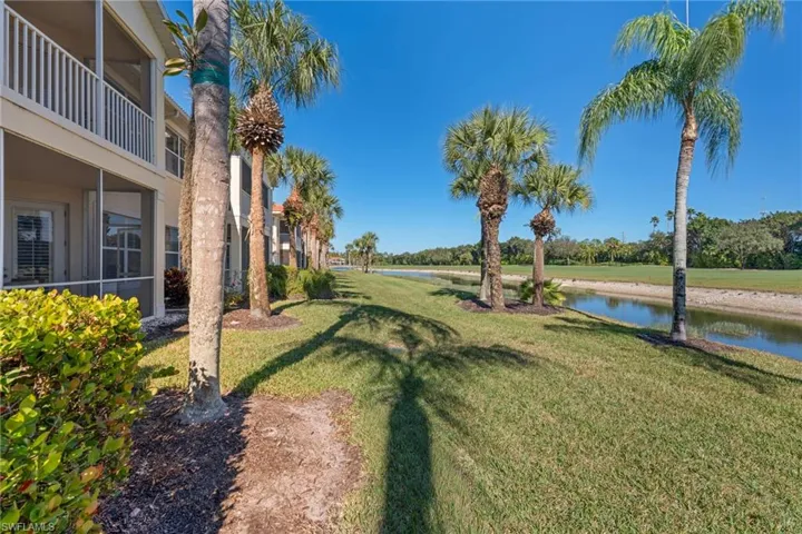 View of grassy yard featuring a sunroom, a water view, and a balcony