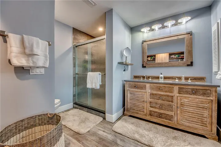 Bathroom with an enclosed shower, toilet, oversized vanity, and hardwood / wood-style floors