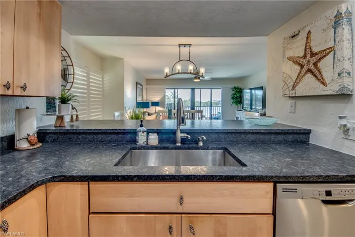 Kitchen with decorative light fixtures, sink, dishwasher, and an inviting chandelier