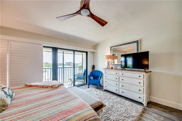 Bedroom with access to outside, ceiling fan, vaulted ceiling, and hardwood / wood-style floors