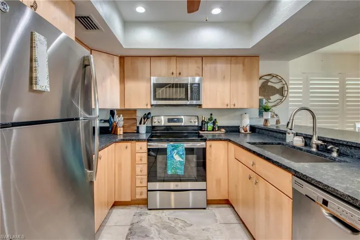 Kitchen with stainless steel appliances, sink, light tile flooring, and light brown cabinets