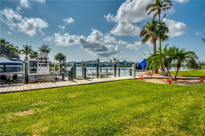 View of dock with a lawn and a water view