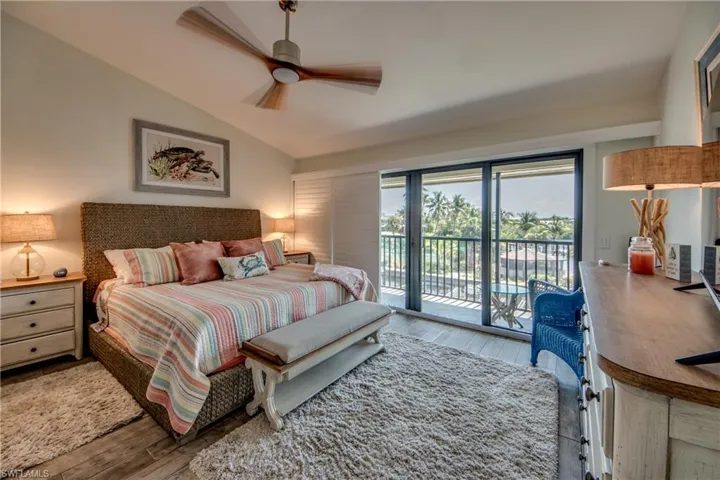 Bedroom with vaulted ceiling, ceiling fan, hardwood / wood-style flooring, and access to exterior