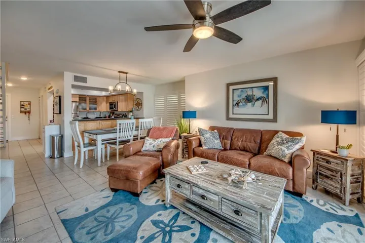 Tiled living room with ceiling fan with notable chandelier