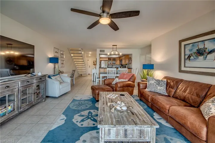 Tiled living room with ceiling fan with notable chandelier