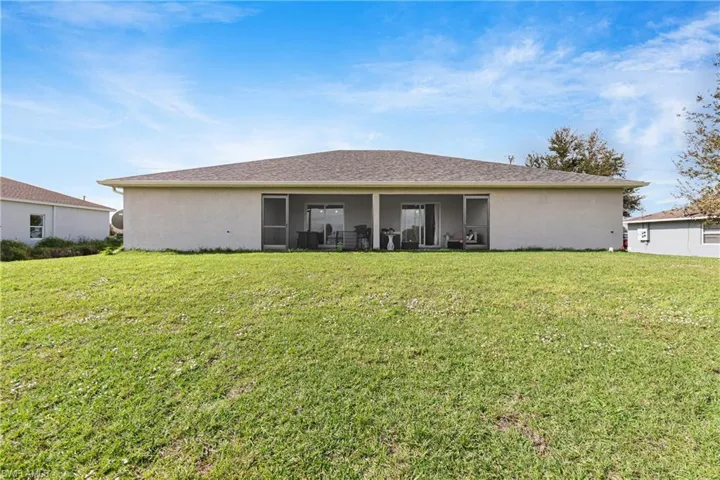 Rear view of property with a lawn and stucco siding