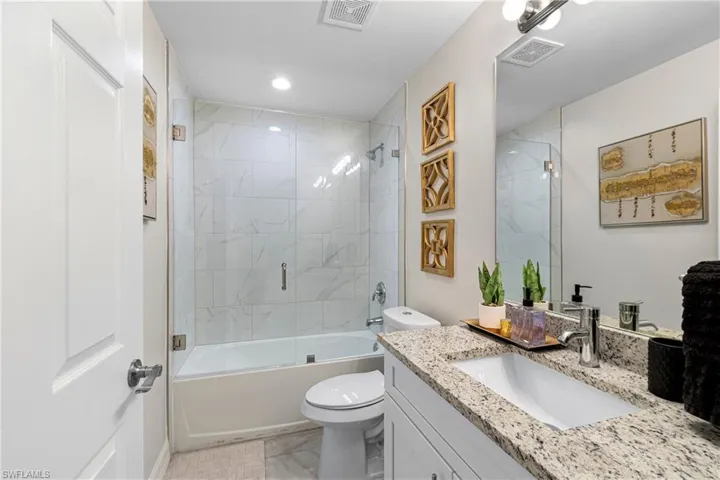Bathroom featuring shower / bath combination with glass door, vanity, and recessed lighting