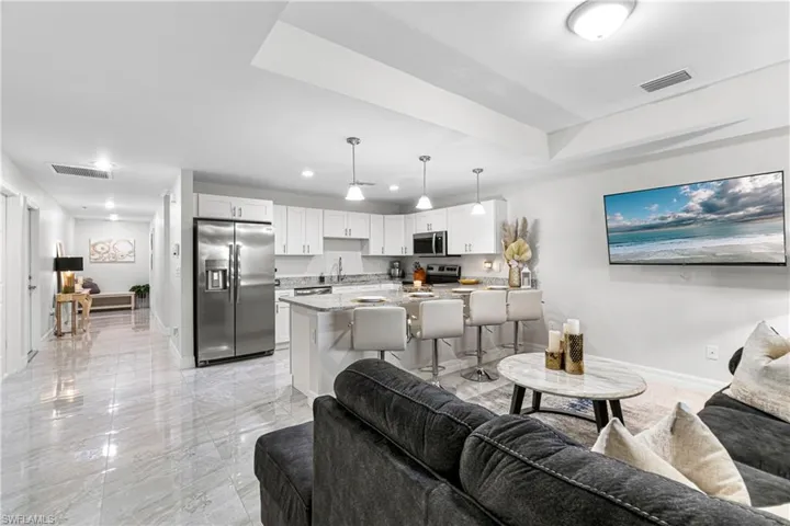 Living area with light marble finish floors and recessed lighting