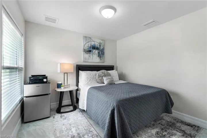 Bedroom with freestanding refrigerator and baseboards