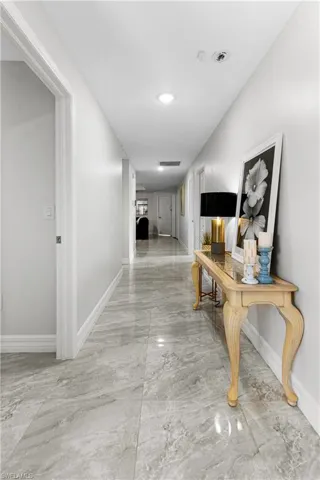 Hallway with light marble finish flooring and recessed lighting