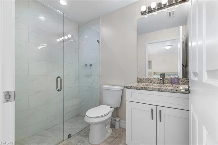 Bathroom featuring a marble finish shower, vanity, and light tile patterned floors