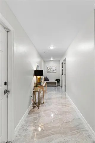 Hallway with light marble finish flooring and baseboards
