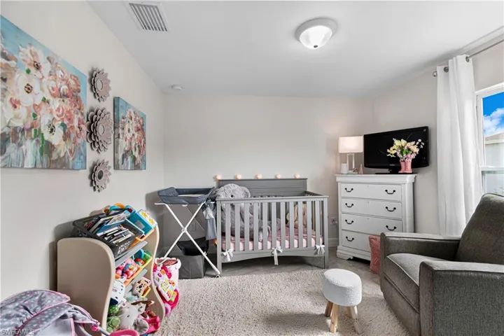 Carpeted bedroom featuring a nursery area