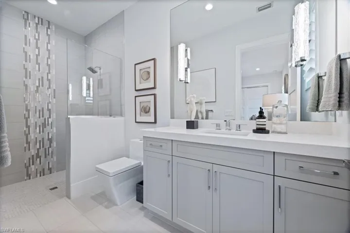 Bathroom with tile patterned floors, toilet, vanity, and tiled shower