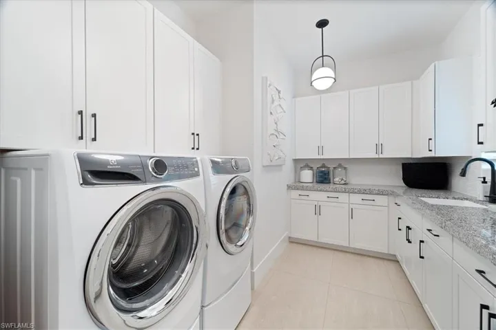 Laundry room featuring cabinets, sink, light tile patterned floors, and washer and dryer