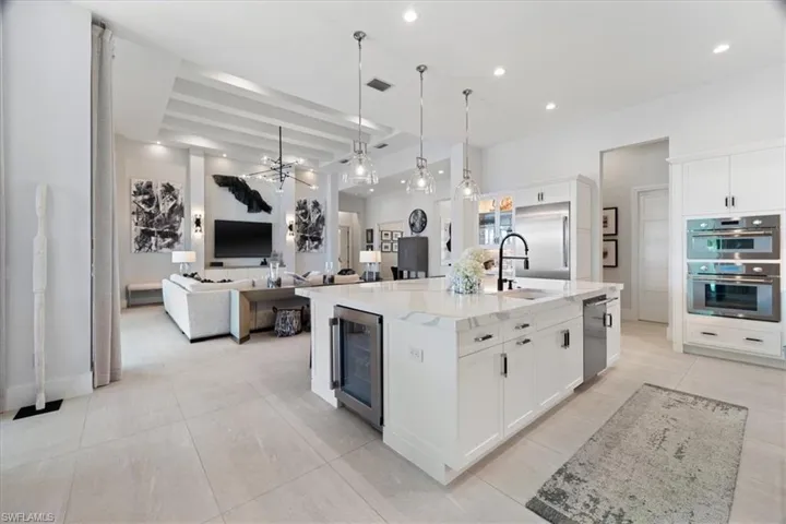 Kitchen with stainless steel appliances, sink, a large island with sink, white cabinetry, and wine cooler