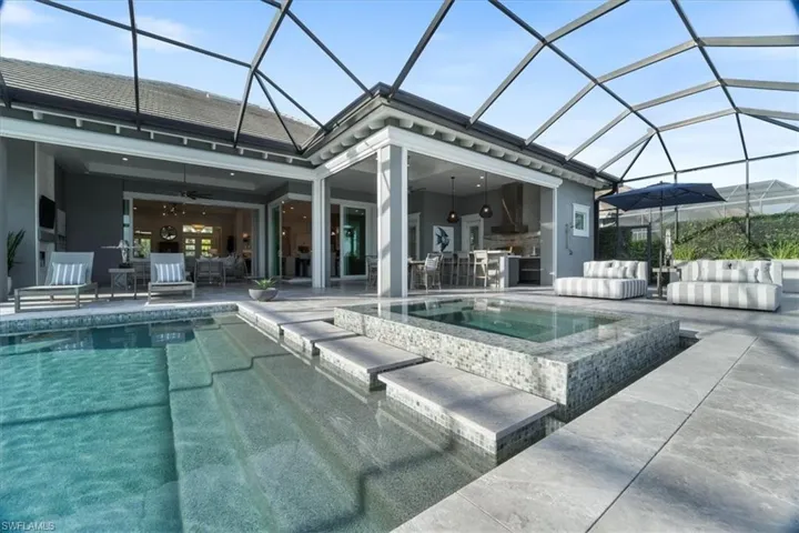 View of swimming pool featuring a patio, ceiling fan, an in ground hot tub, and glass enclosure